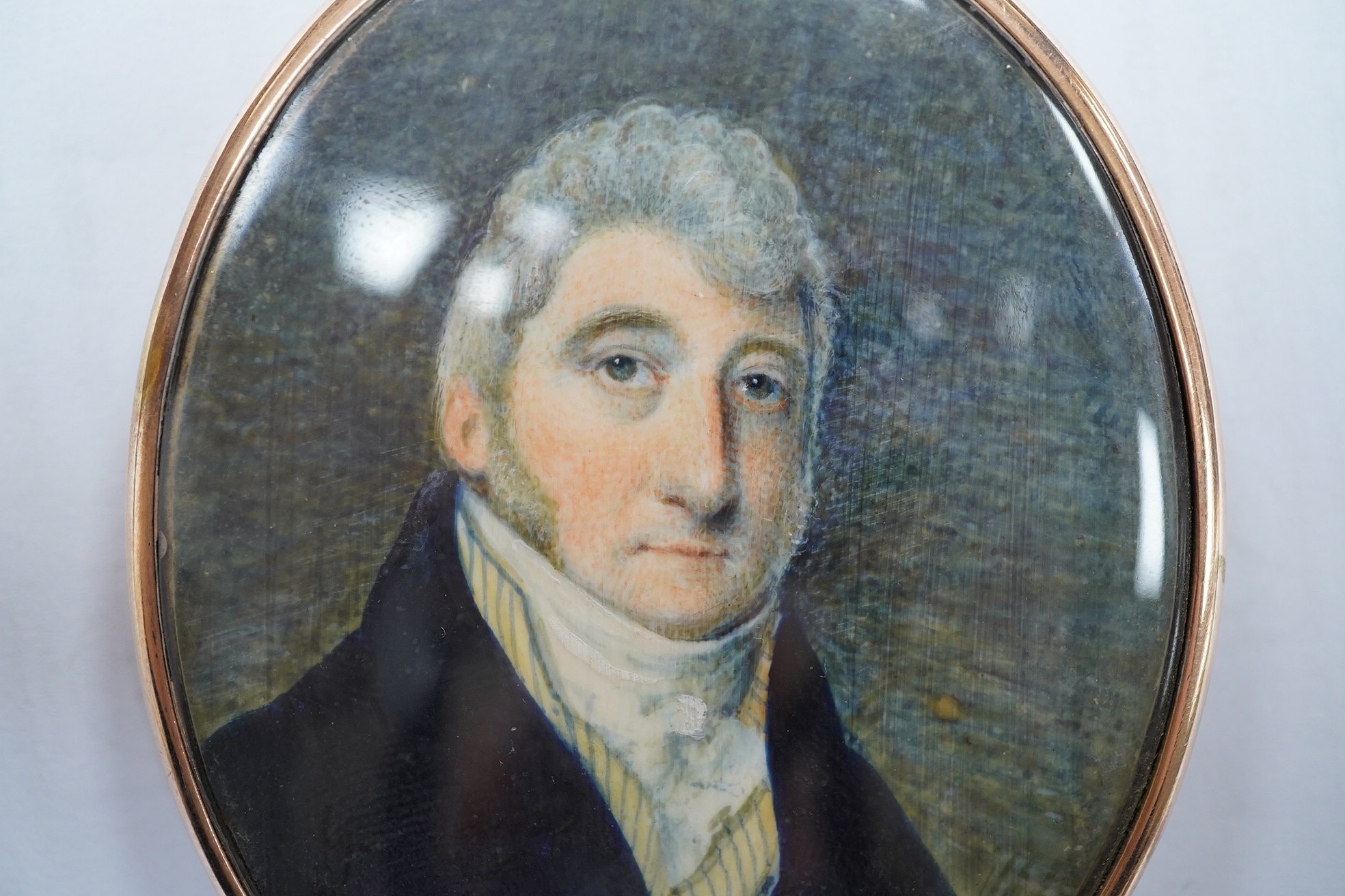 A George III oval portrait miniature on ivory, portrait of a gentleman, lock of hair verso, 6.5cm high, housed in a yellow metal case. Condition - good. CITES Submission reference, 6LF46WVD